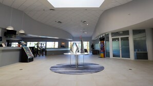 Eine geräumige Lobby mit hoher Decke, einem runden Tisch in der Mitte und einer Rezeption.