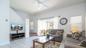 Ein Wohnzimmer mit Fernseher, Sofa, Couchtisch und Deckenventilator.