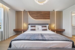 A modern bedroom with a large bed, bedside tables, and a built-in wooden headboard. - Designer 5BR GameLoft, Foam Pit & Lazy River 16164 (Clermont)