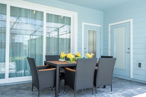A patio with a table and chairs, a glass door, and a white door. - Magical 5Bd Themed w/ Waterpark Near Disney 16161 (Clermont)