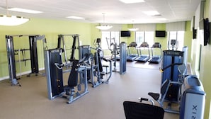 Une salle de sport équipée de divers appareils d’exercice, de tapis de course et d’un espace dédié à la musculation.