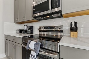Une cuisine moderne équipée d’appareils électroménagers en acier inoxydable, d’un four à micro-ondes et d’un bloc à couteaux.