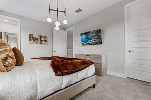Une chambre à coucher avec un lit, une commode, un tableau et une porte.