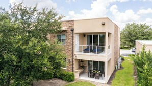 Un edificio moderno su due piani con un balcone, posti a sedere all'aperto e una zona barbecue.