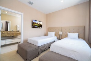 Ett hotellrum med två sängar, ett badrum med spegel och handfat samt en tv på väggen.