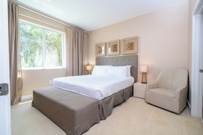 Une chambre d’hôtel avec un grand lit, une chaise, une table de chevet et une fenêtre avec des rideaux.