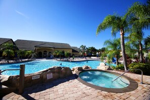A pool area with multiple pools, palm trees, and a building in the background. - Paradise 4Bd w Private Pool & Waterpark 2941 (Kissimmee)