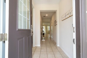 A hallway with a door on the left, a window, and a sign on the right. - Stunning 4Bd w Pool Gameroom Solara Resort 9008 (Kissimmee)