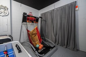 A basketball hoop, a couch, and a curtain in a room with white brick walls. - Stunning 4Bd w Pool Gameroom Solara Resort 9008 (Kissimmee)