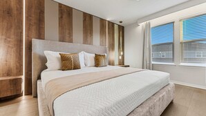 Une chambre à coucher avec un grand lit, des lambris en bois sur les murs, une table de chevet et une fenêtre avec des stores.