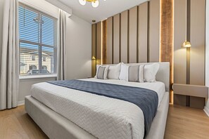 Ein modernes Schlafzimmer mit einem großen Bett, einem Fenster mit Jalousien und einer Wandleuchte.