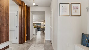Un couloir aux murs recouverts de lambris en bois, doté d’un sol carrelé et orné de certificats encadrés.