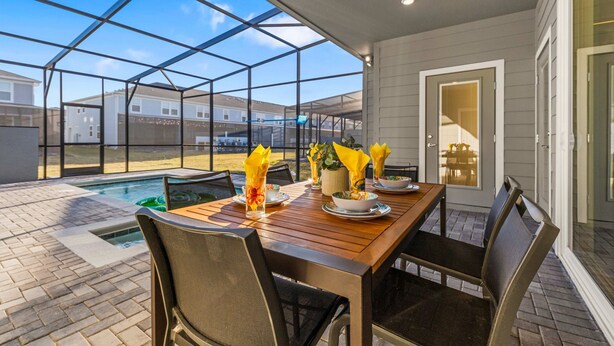 Un patio couvert avec une piscine, une table à manger, des chaises et un ventilateur de plafond.