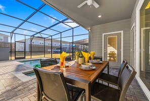 A covered patio with a pool, dining table, chairs, and a ceiling fan. - Stunning 5Bd w Pool & Game Room Near Disney 16165 (Clermont)