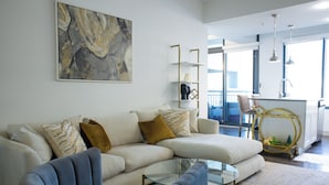 Una sala moderna con un sofá modular, una mesa de centro de vidrio y un sillón azul.