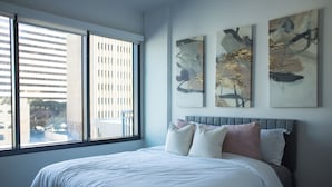 Un dormitorio moderno con una cama grande, una ventana con persianas y arte abstracto en la pared.