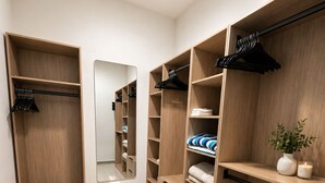 A walk-in closet with wooden shelving, a mirror, and a bench. - Luxury 6BR Villa Near Eagle Beach with Pool, Volleyball & Putting Green (Oranjestad)