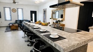 A modern kitchen with a long island, bar stools, and a large mirror. - Luxury 6BR Villa Near Eagle Beach with Pool, Volleyball & Putting Green (Oranjestad)