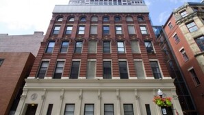 A multi-story building with a classic architectural style, featuring a prominent entrance with a white facade and a large window at the ground level. - Pet Friendly Studio | Walk to MGH (Boston)