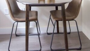 Uma sala de jantar com uma mesa redonda, quatro cadeiras e dois vasos decorativos.