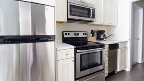 Uma cozinha moderna com eletrodomésticos de aço inoxidável, incluindo geladeira, micro-ondas, fogão e forno.