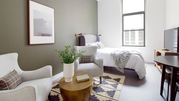 Quarto moderno com cama, sofá, mesa de centro e televisão.