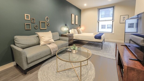 Ein modernes Wohnzimmer mit einer Couch, einem Bett, einem Couchtisch und einem Fernseher.