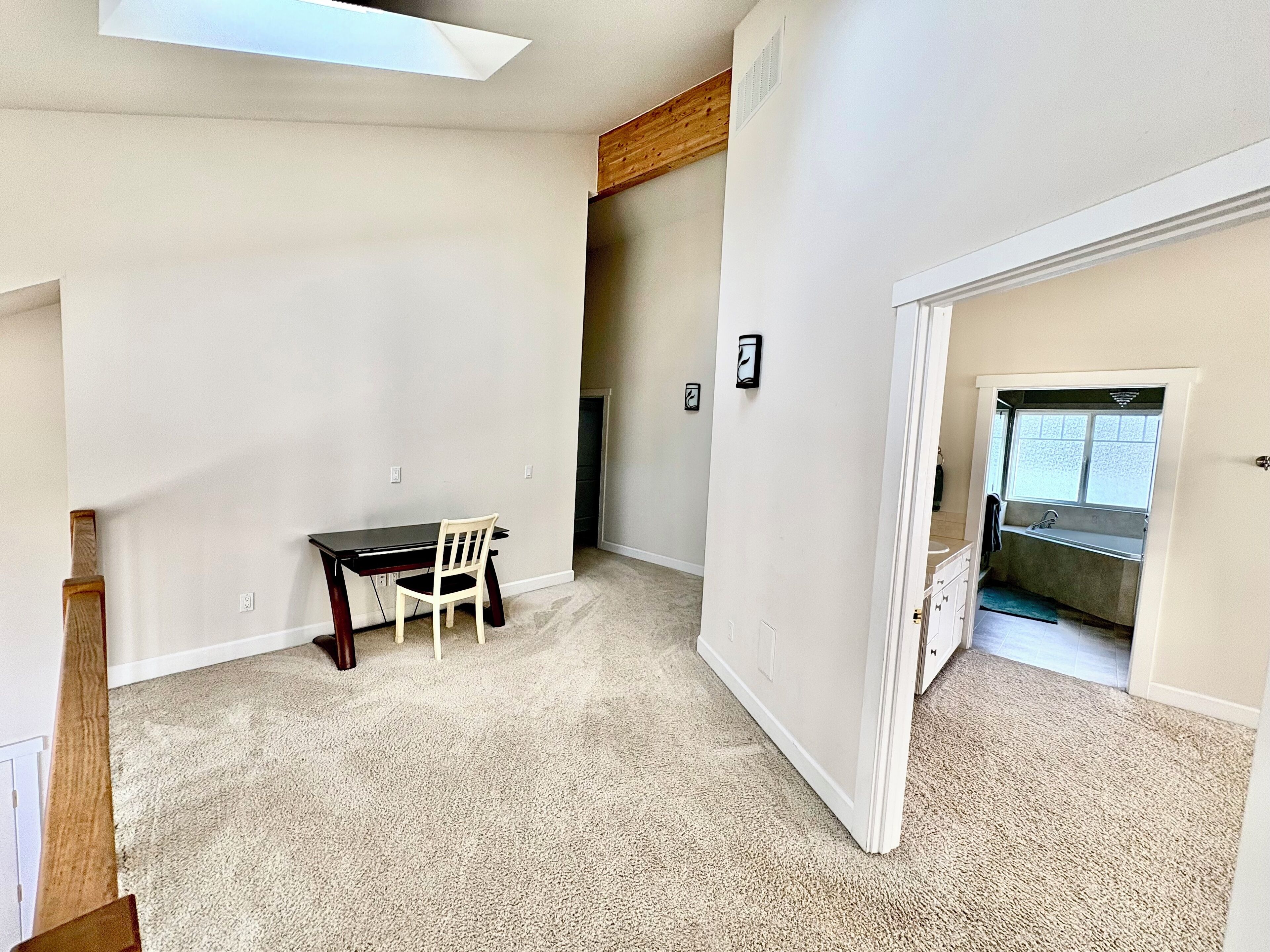 A spacious room with a dining table and chairs, a small window, and a door leading to a bathroom.