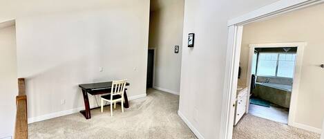 A spacious room with a dining table and chairs, a small window, and a door leading to a bathroom.