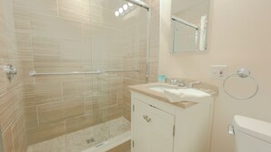Een badkamer met douche, wastafel en toilet.