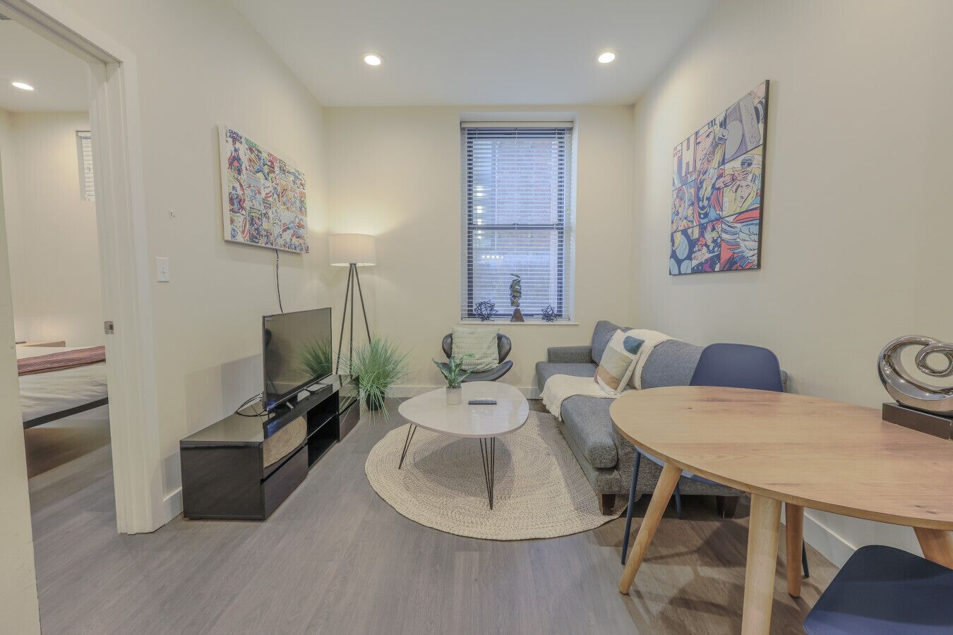 A modern living room with a flat-screen TV, a round coffee table, a sofa, and a dining table.