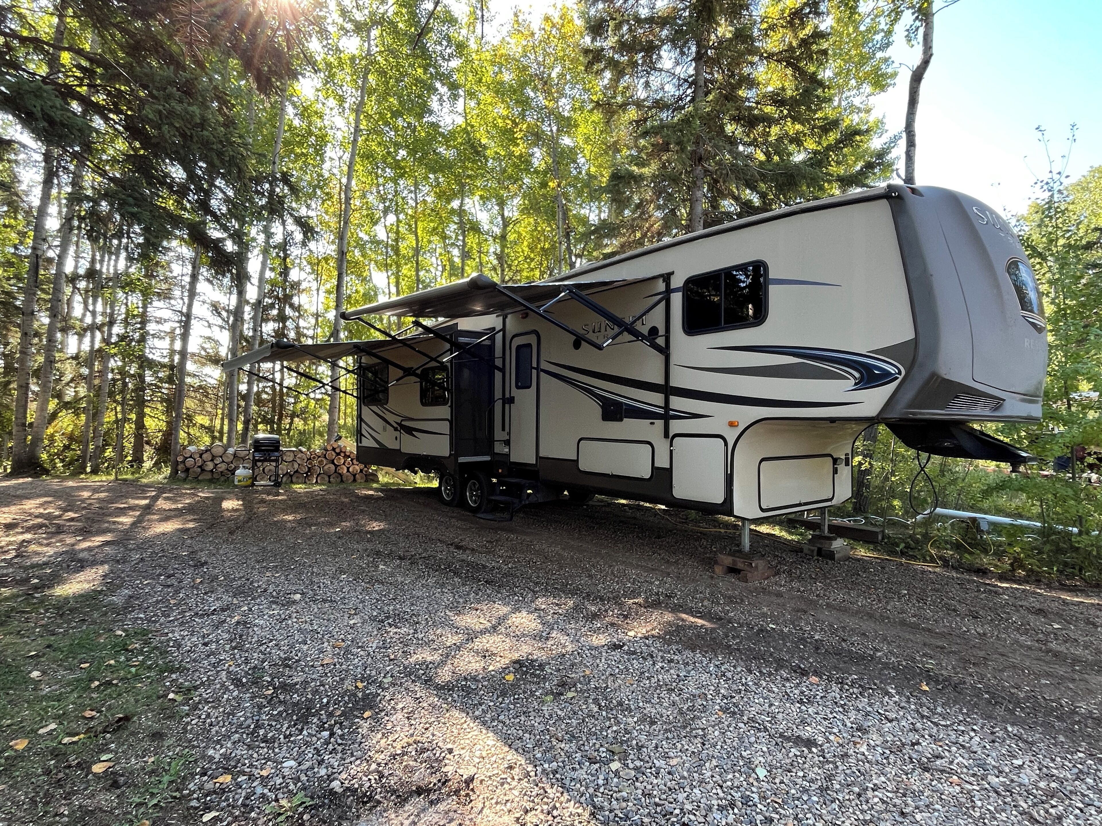 A recreational vehicle parked on a gravel path surrounded by trees.