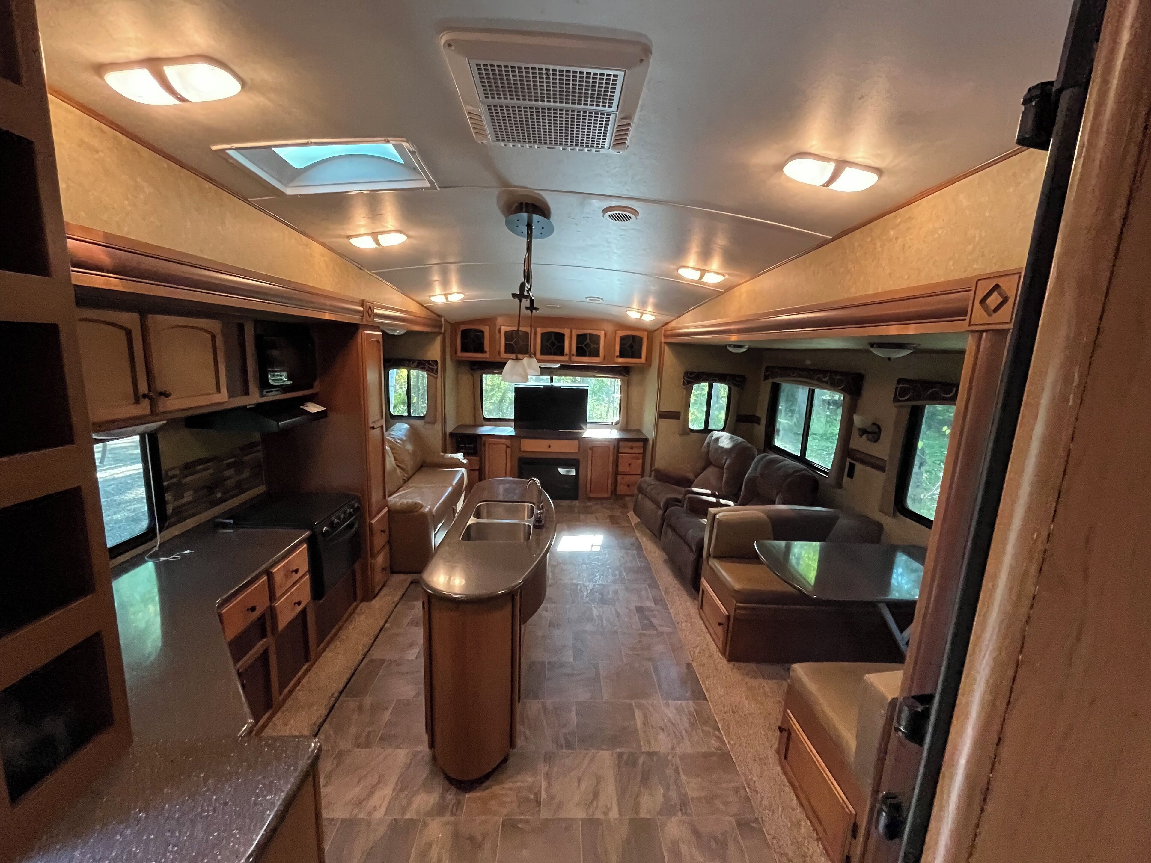 Un intérieur de camping-car bien éclairé, comprenant une cuisine, un coin repas et un espace salon.