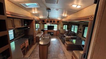 Un intérieur de camping-car bien éclairé, comprenant une cuisine, un coin repas et un espace salon.