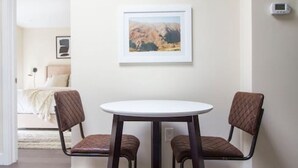 A dining area with a round table and two chairs, a framed picture on the wall, and a thermostat on the wall. - Downtown Boston | Nurses Welcome | W/D in bldg (Boston)