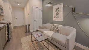 A modern living room with a sofa, a coffee table, and a painting on the wall. - Serene Studio | Close to MGH (Boston)