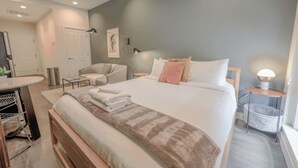 A modern bedroom with a large bed, bedside tables, a chair, a desk, and a wardrobe. - Serene Studio | Close to MGH (Boston)