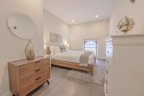 Una camera da letto con un letto, una cassettiera in legno, un comodino e uno specchio a parete.