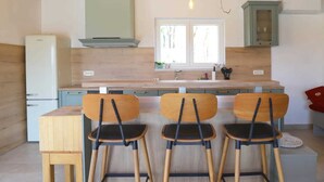 A kitchen with a wooden ceiling, a window, a sink, and three wooden chairs. - Villa ULIKA with private pool and sauna (Malinska)