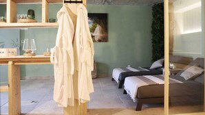 A room with a wooden table, two beds with striped bedding, and a hanging garment rack. - Villa ULIKA with private pool and sauna (Malinska)