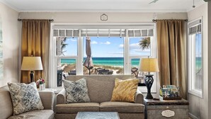 A living room with a view of the ocean, a sofa, a coffee table, and a side table with a lamp and a decorative box.