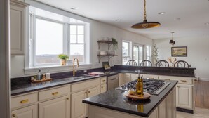A spacious kitchen with a large island, white cabinetry, and a black granite countertop.