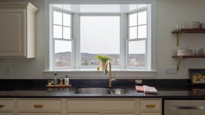 A kitchen with a large window, a sink, and a countertop with various items.