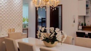 A dining area with a chandelier, white chairs, a table, and a vase of flowers. - @durhambeachhouse your vacation home in Porto Seguro. Comfort and privacy. (Porto Seguro)