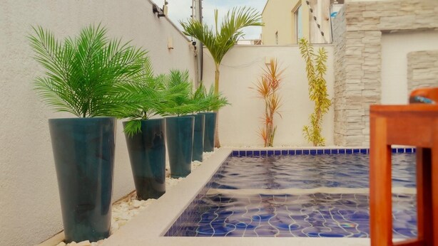 A small outdoor area with a tiled pool, potted plants, and a stone wall. - @durhambeachhouse your vacation home in Porto Seguro. Comfort and privacy. (Porto Seguro)