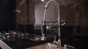 Una cocina moderna con un lavamanos de acero inoxidable, un grifo de cuello alto y un salpicadero de mármol.