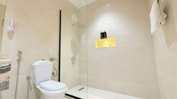 Une salle de bain moderne équipée de toilettes, d’une douche et d’un espace de douche vitré.