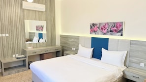 Une chambre d’hôtel moderne avec un grand lit, une coiffeuse avec un miroir et des œuvres d’art accrochées au mur.