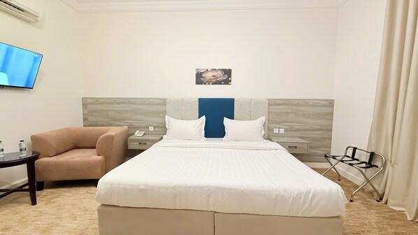 A hotel room with a bed, a chair, a desk, a TV, and a painting on the wall. - Sadeem Al Fkhr (Taif)