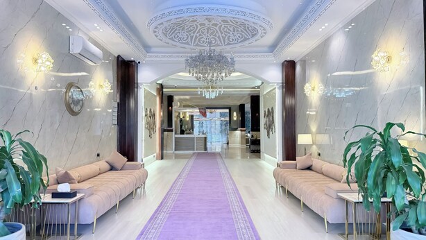 A luxurious hotel lobby with a marble floor, plush sofas, a purple carpet, and a grand chandelier. - Sadeem Al Fkhr (Taif)